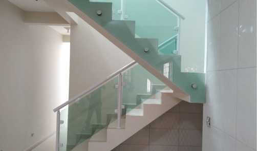 Corrimão de escada com vidro verde em sala residencial